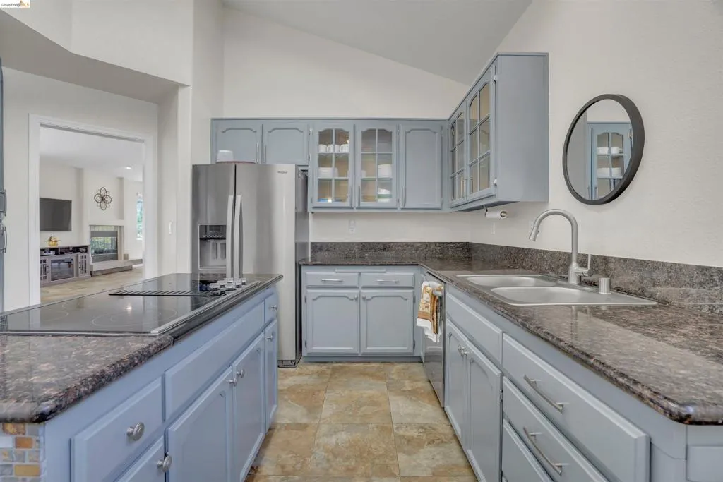 Kitchen featuring light blue cabinetry and dark stone countertops