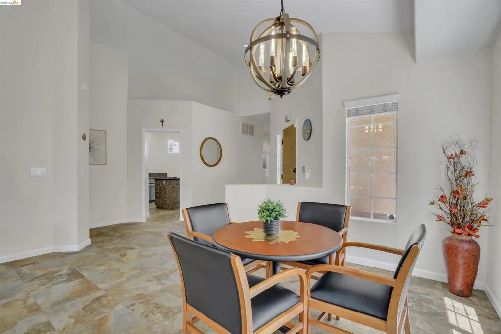Dining area featuring an orb-style chandelier, multi-toned tile flooring, and vaulted ceilings