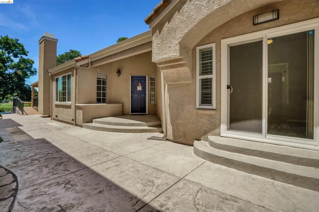Exterior stucco finish with a dark blue front door and arched entryway