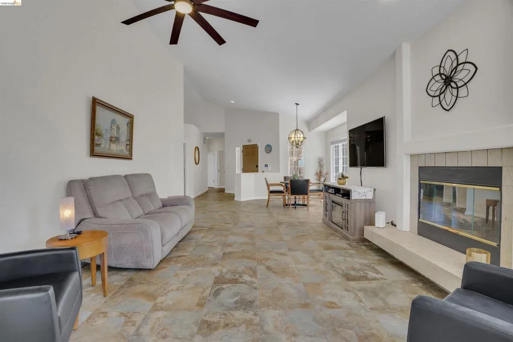 Spacious living area featuring vaulted ceilings, a ceiling fan, and large format tile flooring