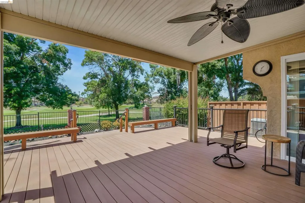 Spacious covered deck featuring composite wood-finish flooring, a ceiling fan, and built-in benches