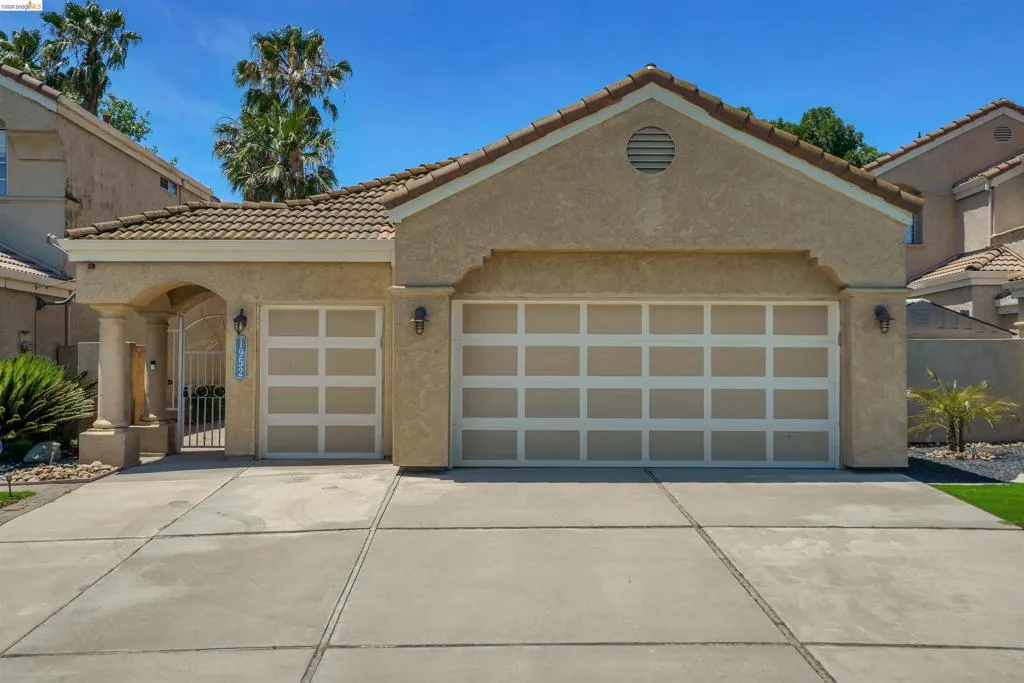 Stucco exterior residence featuring a tile roof and a two-car garage
