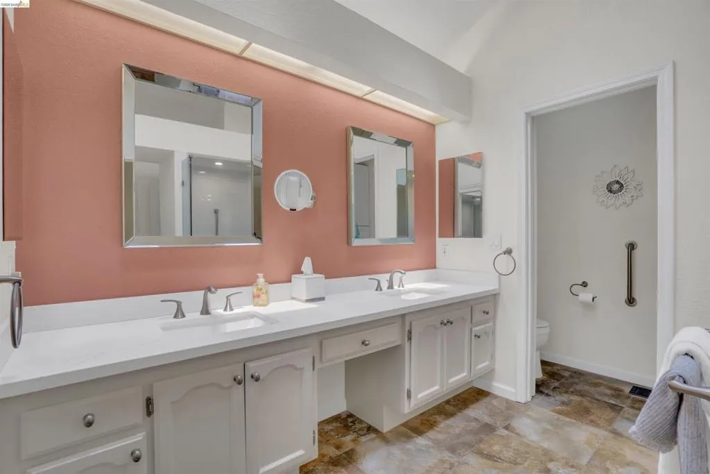 Dual vanity with white countertops and integrated sinks, complemented by a muted red accent wall