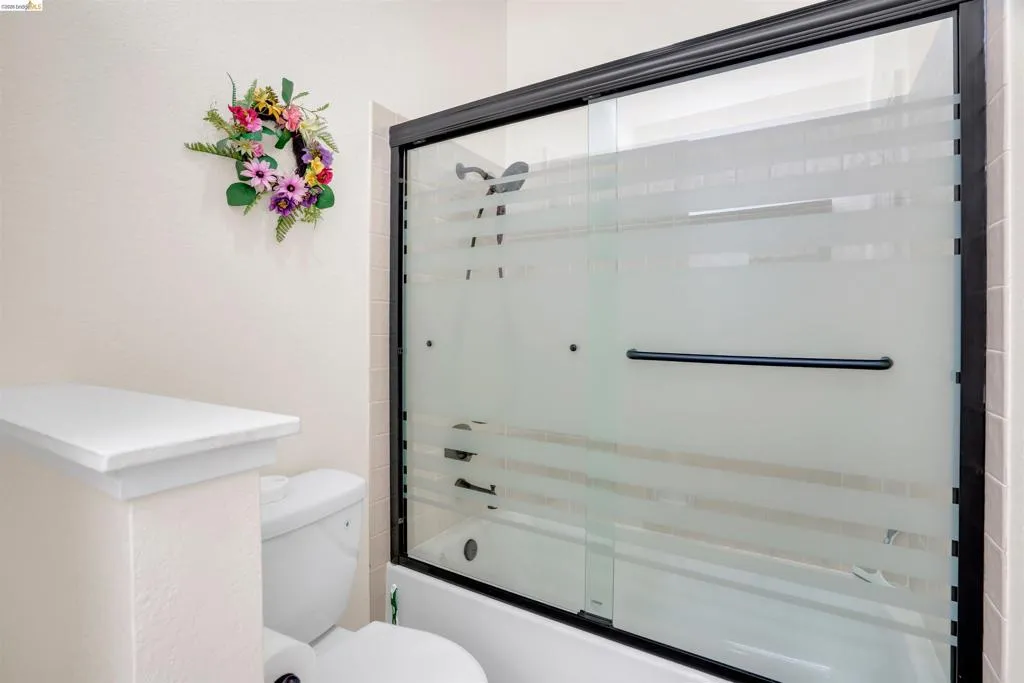 Shower-tub combination featuring a sliding glass enclosure with dark framing and a white acrylic tub