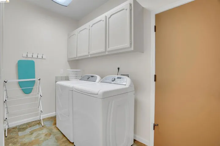 Dedicated laundry area featuring overhead cabinetry, a tile backsplash, and durable flooring