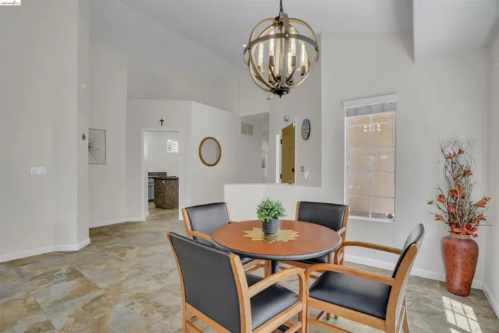Dining area featuring an orb-style chandelier, multi-toned tile flooring, and vaulted ceilings
