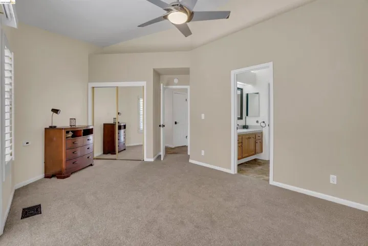 Carpeted room featuring a vaulted ceiling with a flush-mount ceiling fan