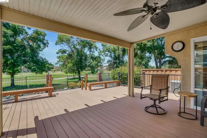 Spacious covered deck featuring composite wood-finish flooring, a ceiling fan, and built-in benches