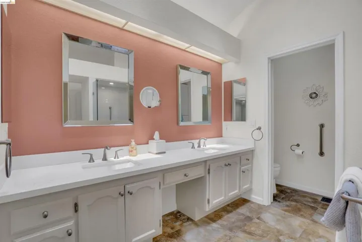 Dual vanity with white countertops and integrated sinks, complemented by a muted red accent wall