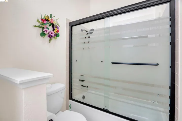 Shower-tub combination featuring a sliding glass enclosure with dark framing and a white acrylic tub