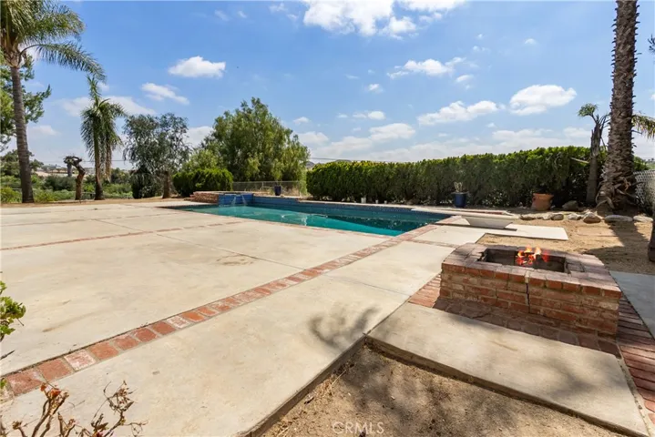 Pool with cement deck, firepit and diving board.