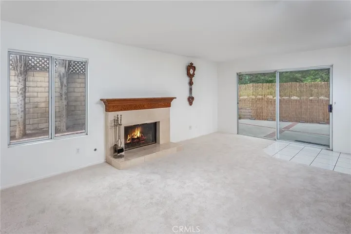 The family room features a gas fireplace, wet bar, dual storage closets, and sliding doors leading directly to the private backyard with tall Cypress trees, raised flowerbeds, lush greenery, brick and concrete patio space, and natural gas hookup for a future BBQ setup. It’s easy to picture movie nights by the fire, holiday gatherings, or slow weekend mornings with the doors open to the backyard while natural light fills the home.