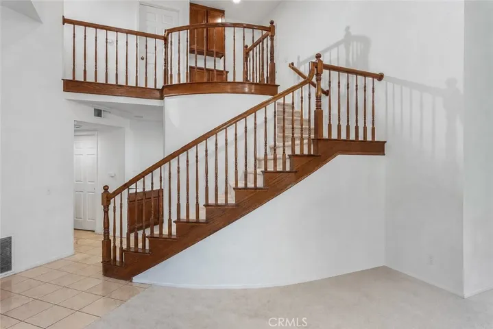 Inside, soaring cathedral ceilings, a dramatic sweeping staircase, and natural light pouring through mullioned windows create an open, airy feel.