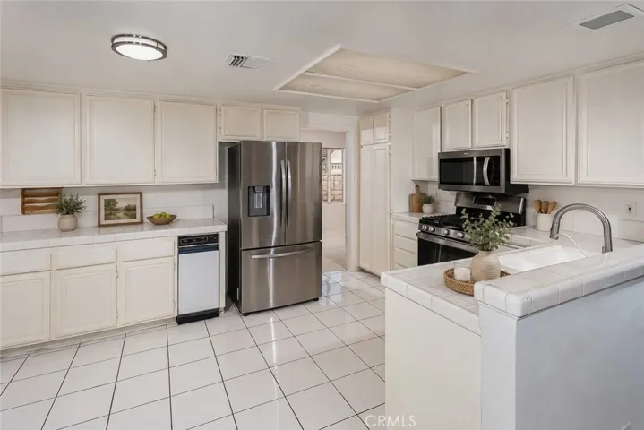 Virtually Staged
The kitchen opens naturally to the family room and sunny breakfast nook, creating a comfortable everyday gathering space. Features include tile floors and counters, stainless steel appliances, GE® 5-burner gas range, Bosch® silent dishwasher, Whirlpool® microwave, Samsung® refrigerator/freezer, pantry storage, trash compactor, and dual basin sink.
