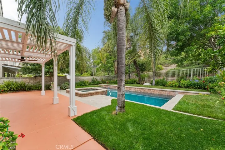 Stunning backyard retreat complete with a sparkling pool, relaxing spa, lush palm trees, and fruit trees.