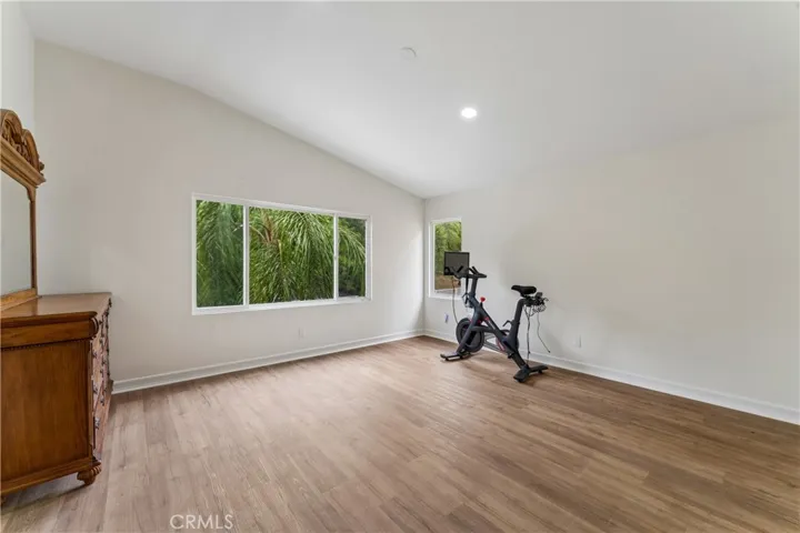 Primary suite featuring vaulted ceilings and a large window with views of the backyard.