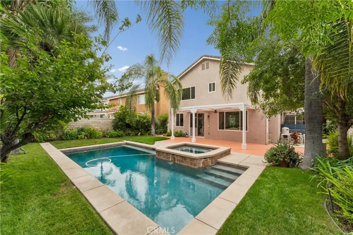 Stunning backyard retreat complete with a sparkling pool, relaxing spa, lush palm trees, and fruit trees.