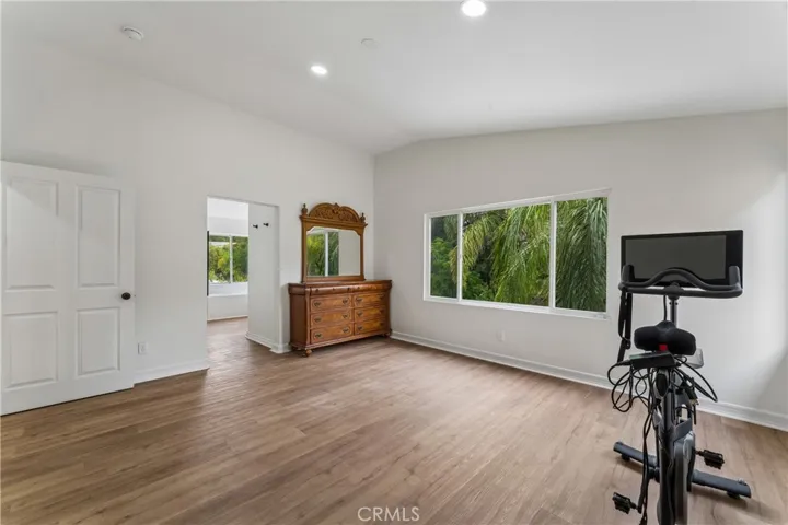 Primary suite featuring vaulted ceilings and a large window with views of the backyard.