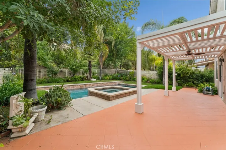 Stunning backyard retreat complete with a sparkling pool, relaxing spa, lush palm trees, and fruit trees.
