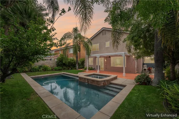 Virtually enhanced Stunning backyard retreat complete with a sparkling pool, relaxing spa, lush palm trees, and fruit trees

