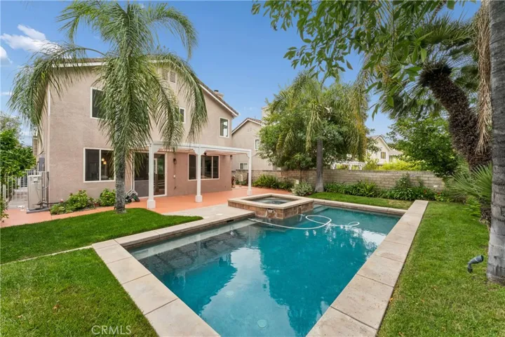 Stunning backyard retreat complete with a sparkling pool, relaxing spa, lush palm trees, and fruit trees.