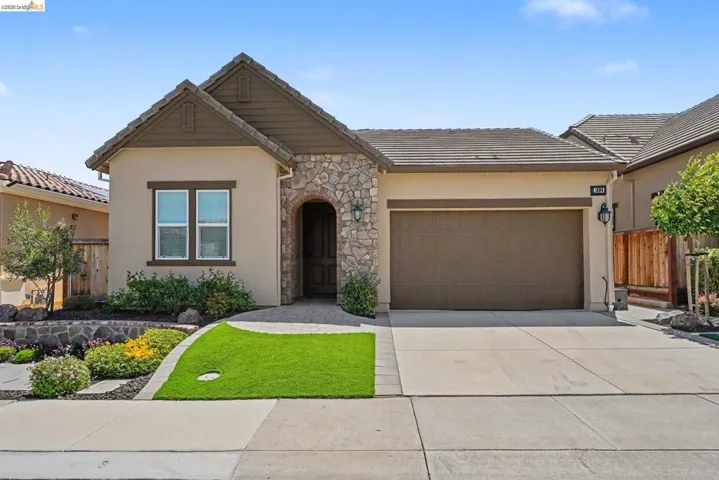 Mediterranean-style exterior featuring a stucco facade, stone accents, and a tile roof