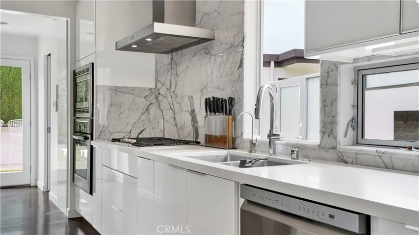Chef’s kitchen boasts stone countertops, stainless steel appliances, and lacquered glass cabinetry.