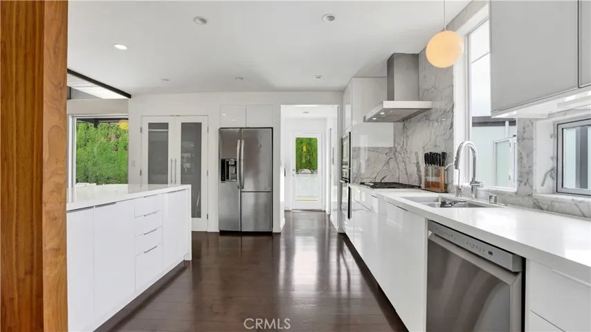 Chef’s kitchen boasts stone countertops, stainless steel appliances, and lacquered glass cabinetry.