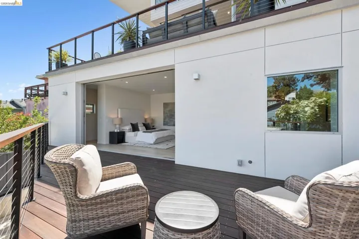 Spacious deck with dark wood-finish flooring and modern cable railings. Primary suite.