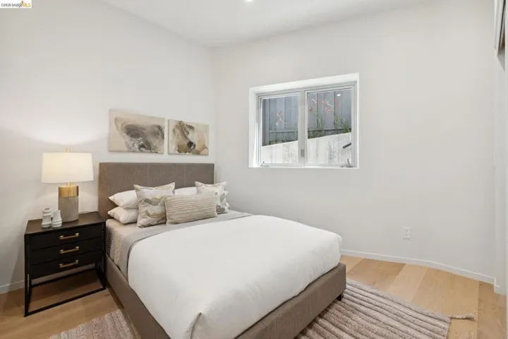 Bedroom featuring light wood-finish flooring, white walls, and a large window