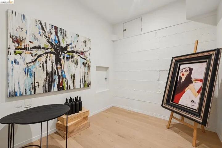 Recessed wall niche, light wood-finish flooring, white painted walls, and built-in upper wall storage