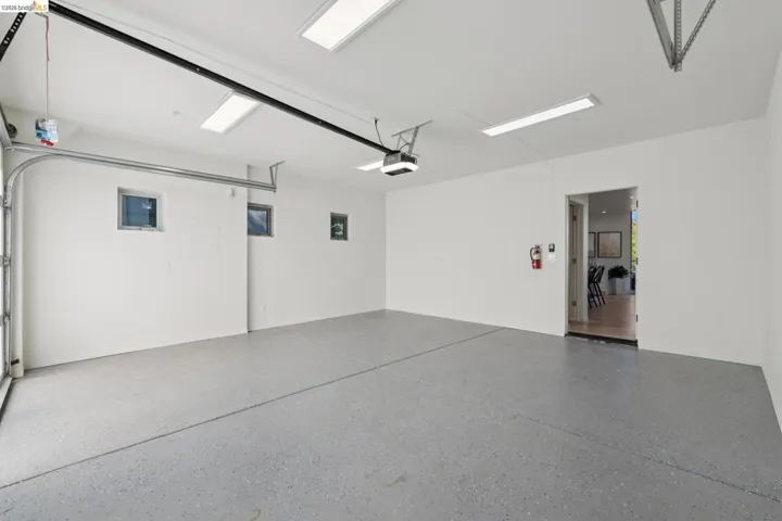 Spacious garage featuring a durable epoxy floor coating, recessed lighting, multiple windows for natural illumination, and an integrated garage door opener system.  Universal Tesla adapter.
