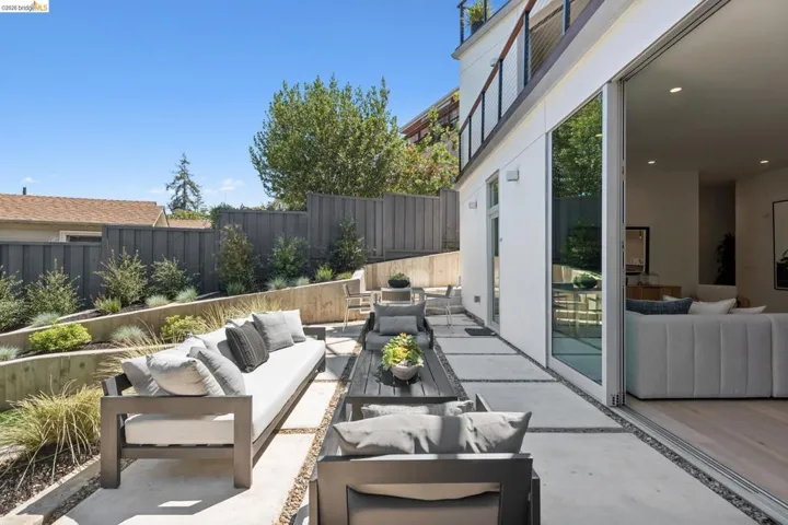 Expansive outdoor patio featuring concrete pavers, gravel accents, and a tiered garden with mature plantings
