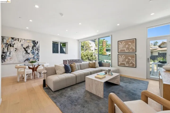 Open-concept living area featuring light wood-finish flooring, recessed lighting, expansive sliding glass doors, and a glass-paneled door