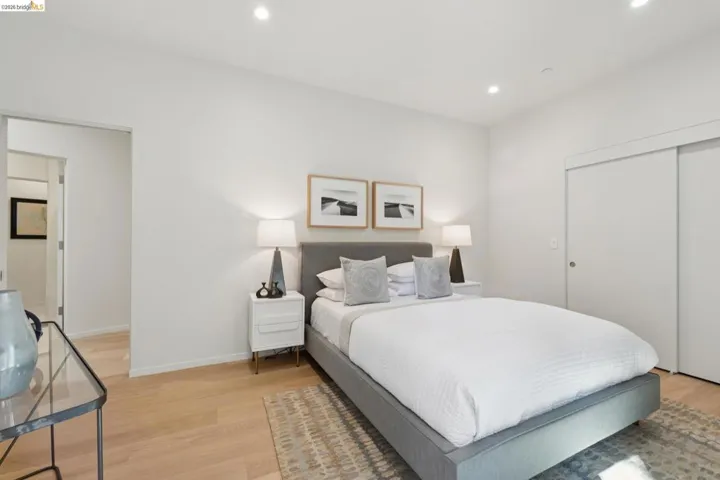 Recessed lighting illuminates a space featuring wood-finish flooring and a minimalist sliding closet door