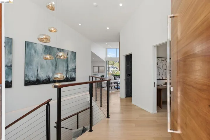 Entryway featuring a large wood-finish door with an elongated metal pull, light wood-finish flooring, recessed lighting, and a modern chandelier