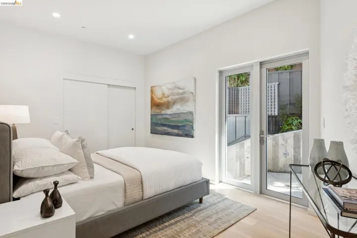 Bedroom featuring direct patio access through a glass-paneled door, recessed ceiling lighting, wood-finish flooring, and a sliding closet door