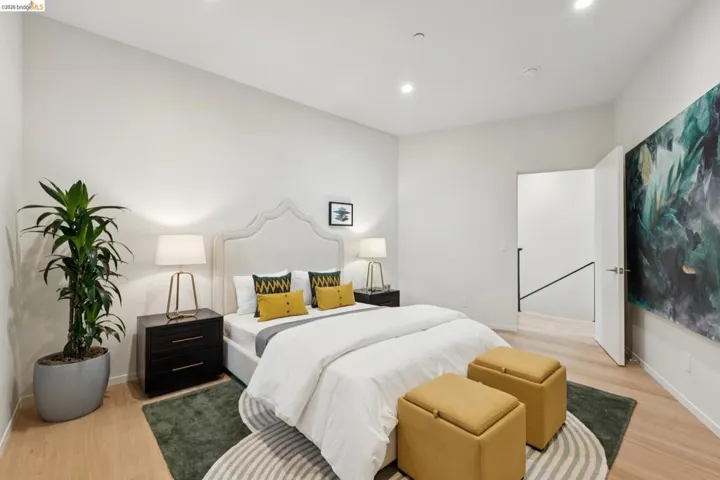 Bedroom with light wood-finish flooring, recessed lighting, and a white upholstered headboard