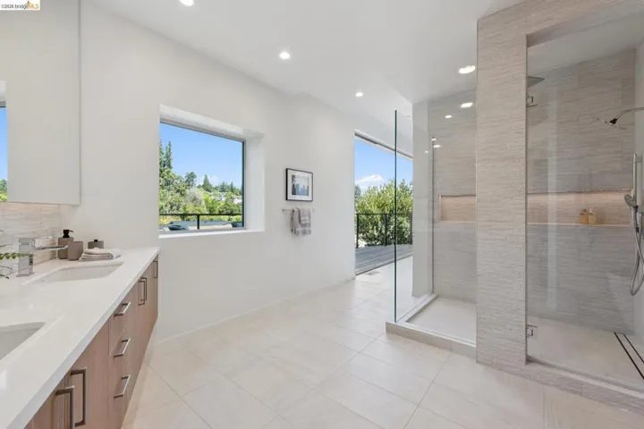 Modern bathroom with a dual vanity featuring wood-finish cabinetry, white countertops, and undermount sinks