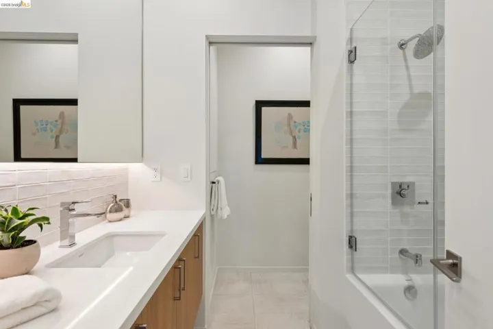 Bathroom featuring a white quartz countertop, wood-finish cabinetry, a built-in rectangular sink, and chrome fixtures