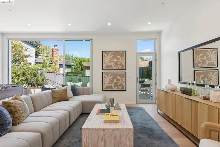 Spacious living area featuring expansive glass sliding doors, recessed lighting, and light wood-finish flooring