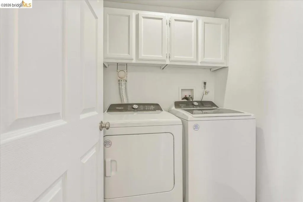 Dedicated laundry space featuring white paneled upper cabinetry, white walls, and a white interior door Dedicated laundry space featuring white paneled upper cabinetry, white walls, and a white interior door