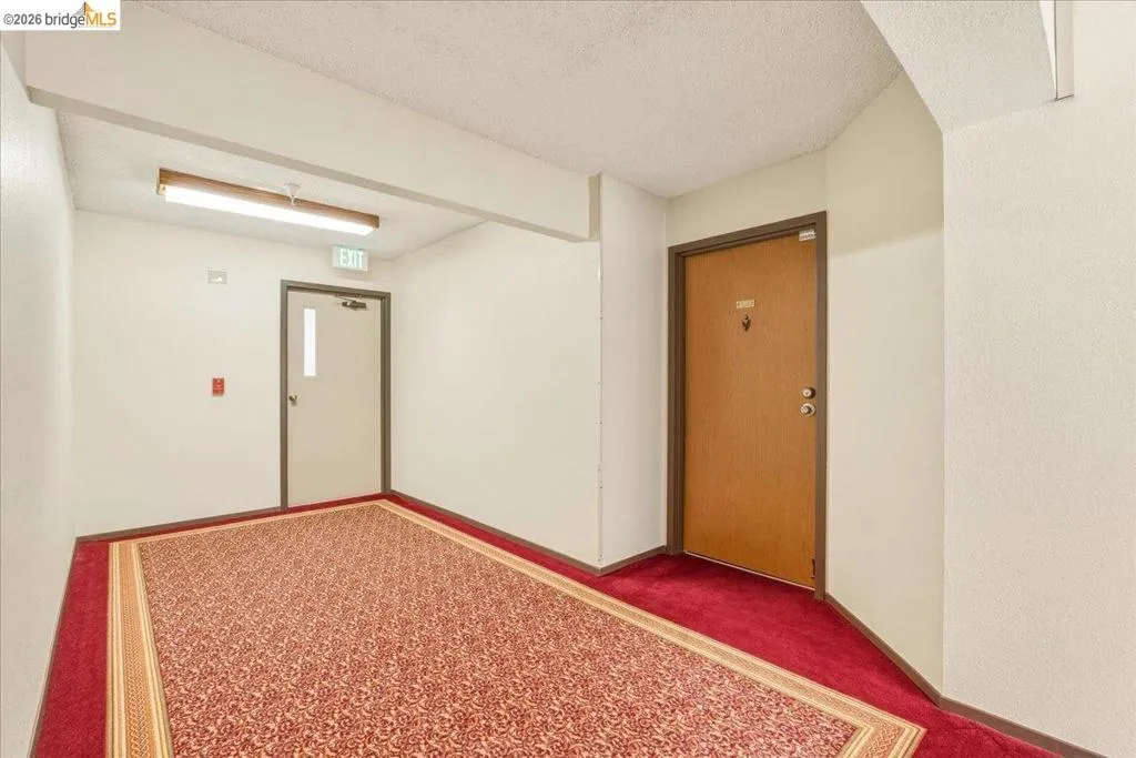 Hallway featuring patterned red carpeting and light-colored walls Hallway featuring patterned red carpeting and light-colored walls