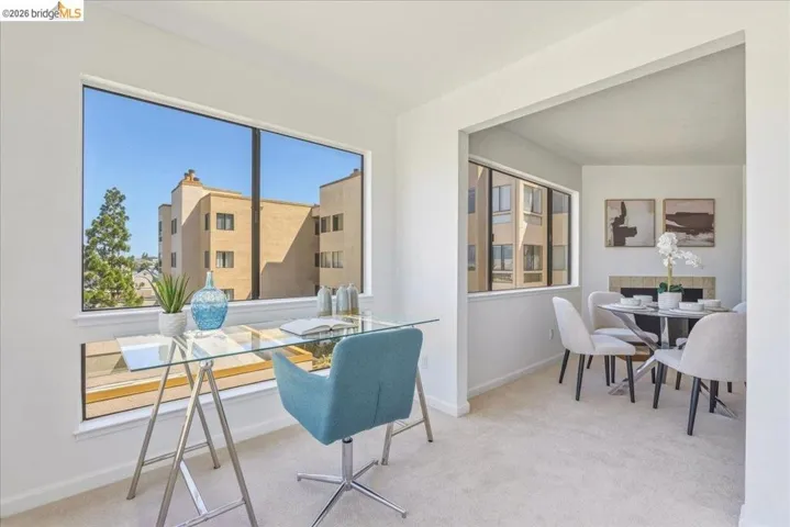 Bright interior space featuring expansive windows, neutral wall tones, and light-toned carpeting