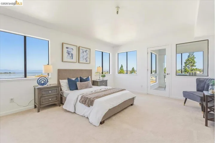 Bedroom featuring multiple windows, light-colored carpeting, white walls, and a glass-paneled door