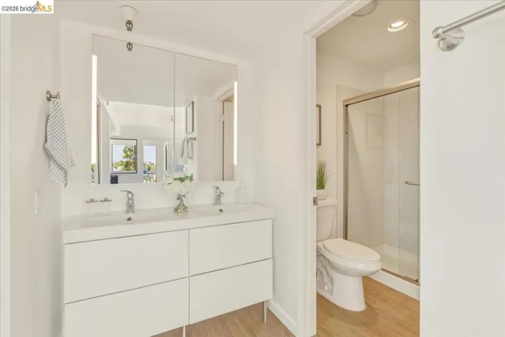 Dual vanity with integrated sinks and chrome fixtures, illuminated medicine cabinet, recessed lighting, and wood-finish flooring