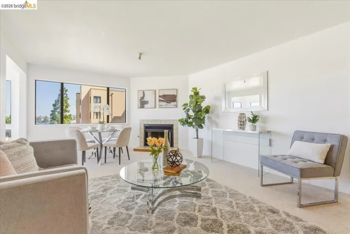 Living area featuring a fireplace with a light tile surround, large windows, and neutral carpeting