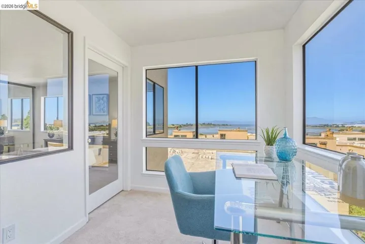 Bright flex space featuring expansive windows, carpeted flooring, a glass panel door, and a built-in window ledge