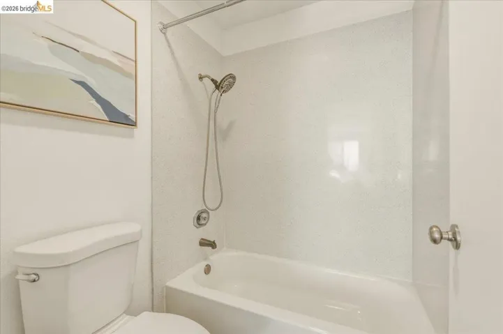 White porcelain bathtub and shower combination featuring a brushed nickel shower head and faucet set