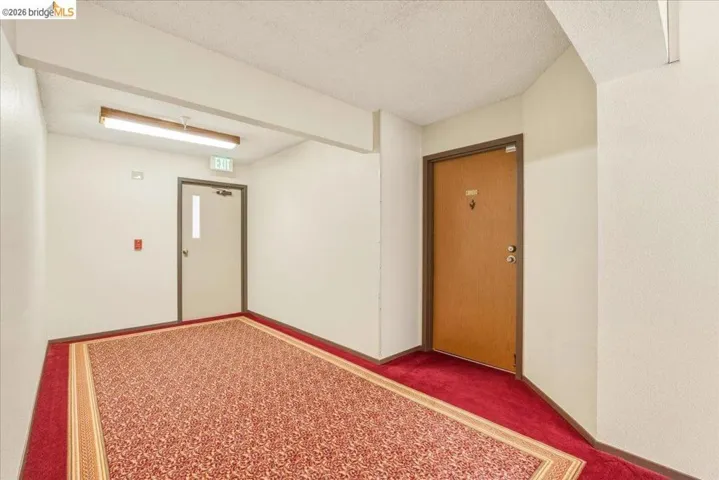 Hallway featuring patterned red carpeting and light-colored walls
